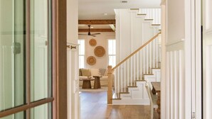 A hallway with a wooden staircase, a woven light fixture, and a glass door.