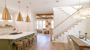 Una cocina amplia con una isla grande, taburetes de bar e iluminación colgante.