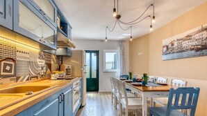 A modern kitchen with blue cabinets, a wooden countertop, and a dining area with a table and chairs. - Villa Leticia Crikvenica Riviera (Hreljin)