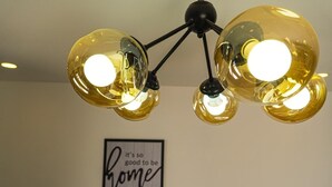 A chandelier with three spherical glass bulbs and a wall-mounted sign that reads "it's so good to be home." - Casa SOFIA, spacious, safe, easy access, pets welcome  (Santa Rosa de Copán)