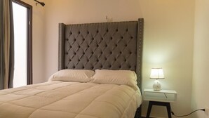 A neatly made bed with a tufted headboard, a bedside table with a lamp, and a power outlet. - Casa SOFIA, spacious, safe, easy access, pets welcome  (Santa Rosa de Copán)