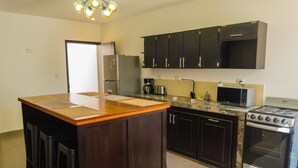 A kitchen with dark wooden cabinets, a central island with stools, a stove, a microwave, and a refrigerator. - Casa SOFIA, spacious, safe, easy access, pets welcome  (Santa Rosa de Copán)