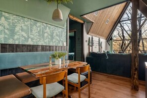 A cozy restaurant with wooden furniture, a high ceiling, and a view of trees. - Evergreen Dreams | A-Frame Retreat + Hot Tub/Sauna (Polk County)