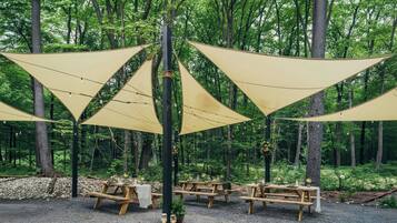 A forested area with picnic tables and triangular shade structures.