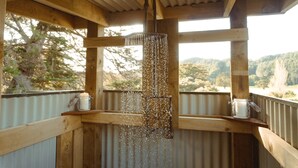 Une structure en bois, dotée d’un luminaire suspendu et offrant une vue sur l’extérieur.