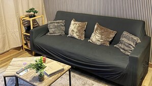 Una sala de estar moderna con un sofá gris oscuro, una mesa de centro de madera y una cortina a rayas.