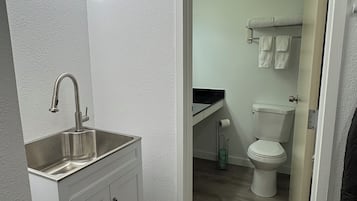 A modern bathroom with a white sink, vanity, and a toilet visible through an open door.