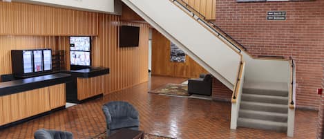 A lobby with a reception desk, seating area, and a staircase.