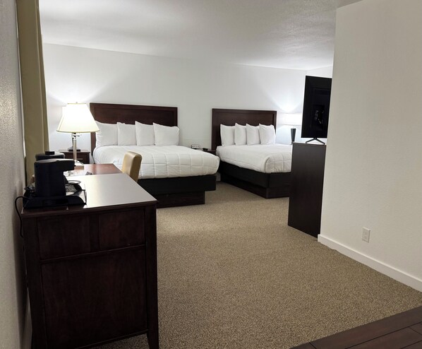 A hotel room with two beds, a desk, a coffee maker, and a TV. - Heritage Hotel Quincy (Quincy)