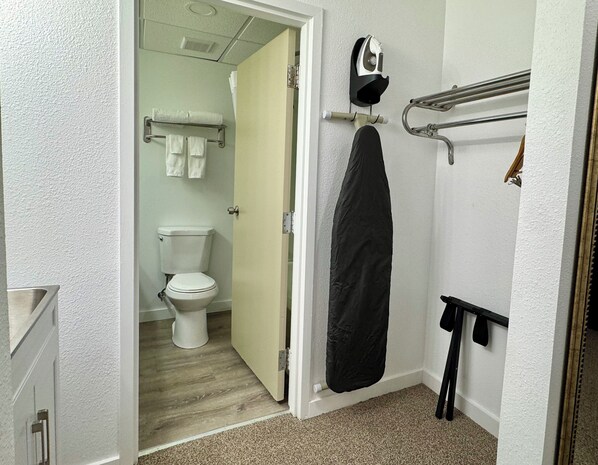A bathroom with a toilet, a towel rack, a shower curtain, and a towel rack with a towel. - Heritage Hotel Quincy (Quincy)
