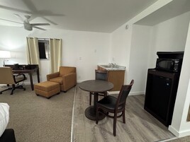 Un espacio habitable compacto con mesa de comedor, dos sillas, un sofá, escritorio y kitchenette.