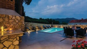 Un espace extérieur avec une piscine, des murs en pierre et une table entourée de chaises.