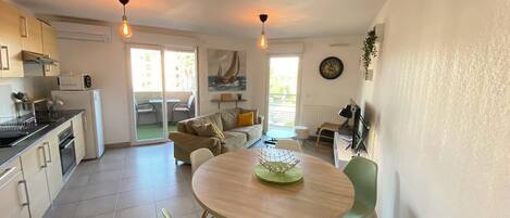 A compact kitchen with a dining area, a sofa, and a TV.