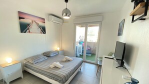 Une chambre à coucher avec un lit, des tables de chevet, une télévision et une vue sur l’extérieur.