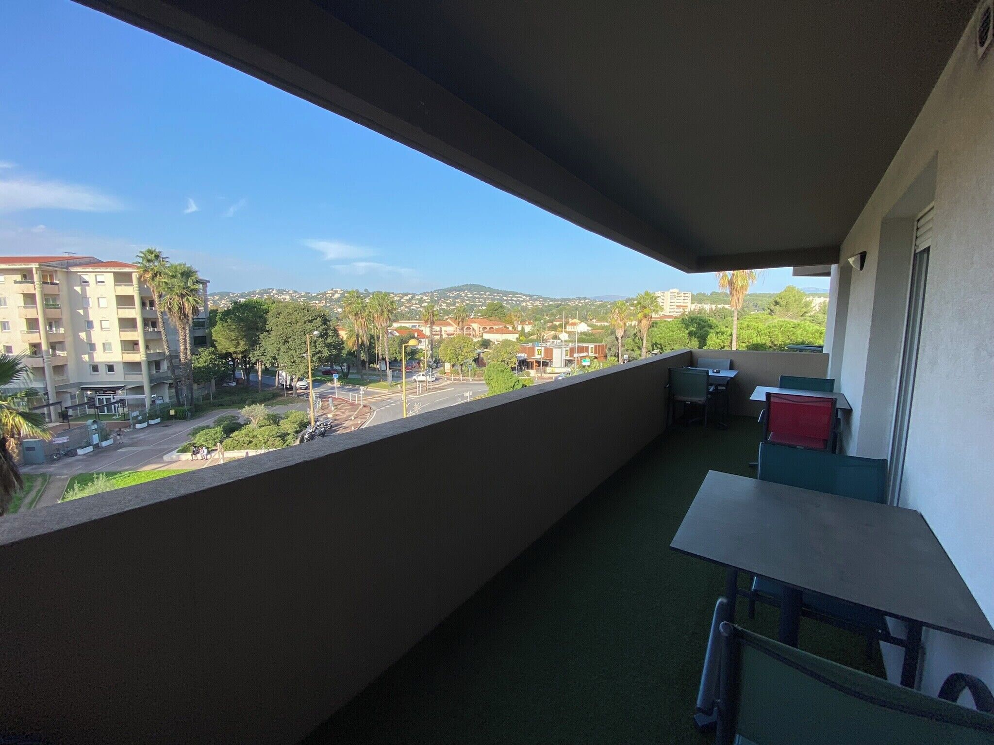 A balcony with a view of a cityscape, including buildings and palm trees.