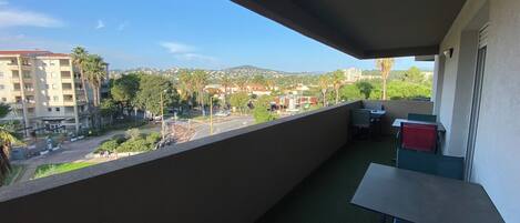 A balcony with a view of a cityscape, including buildings and palm trees.
