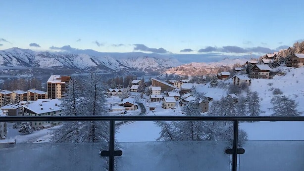 A snow-covered village with buildings and mountains in the background.