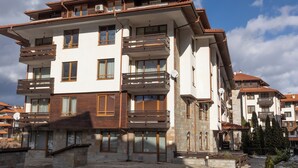 A multi-story building with balconies, large windows, and a stone facade.
