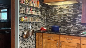 A kitchen with wooden cabinets, a tiled backsplash, a clock, and various kitchen utensils. - Thousand Island Park home, 5 bedroom,  3 and 1/2 bath, with dock space!! (Fineview)