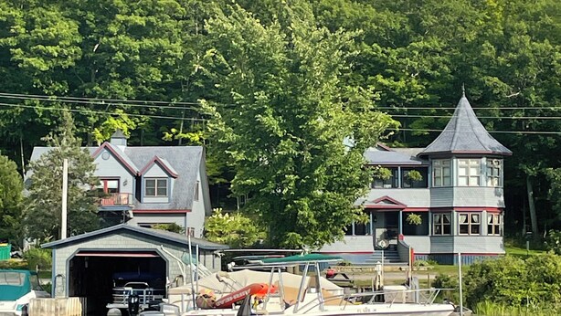 A waterfront property with a dock, a covered boat storage area, and a house with a distinctive tower. - Thousand Island Park home, 5 bedroom,  3 and 1/2 bath, with dock space!! (Fineview)
