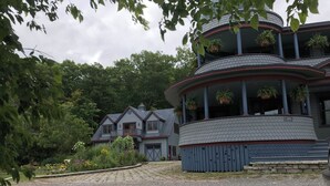 A multi-story building with a curved roof and a balcony with hanging plants. - Thousand Island Park home, 5 bedroom,  3 and 1/2 bath, with dock space!! (Fineview)