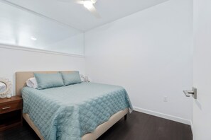 A bedroom with a bed, a nightstand, a mirror, and a door.