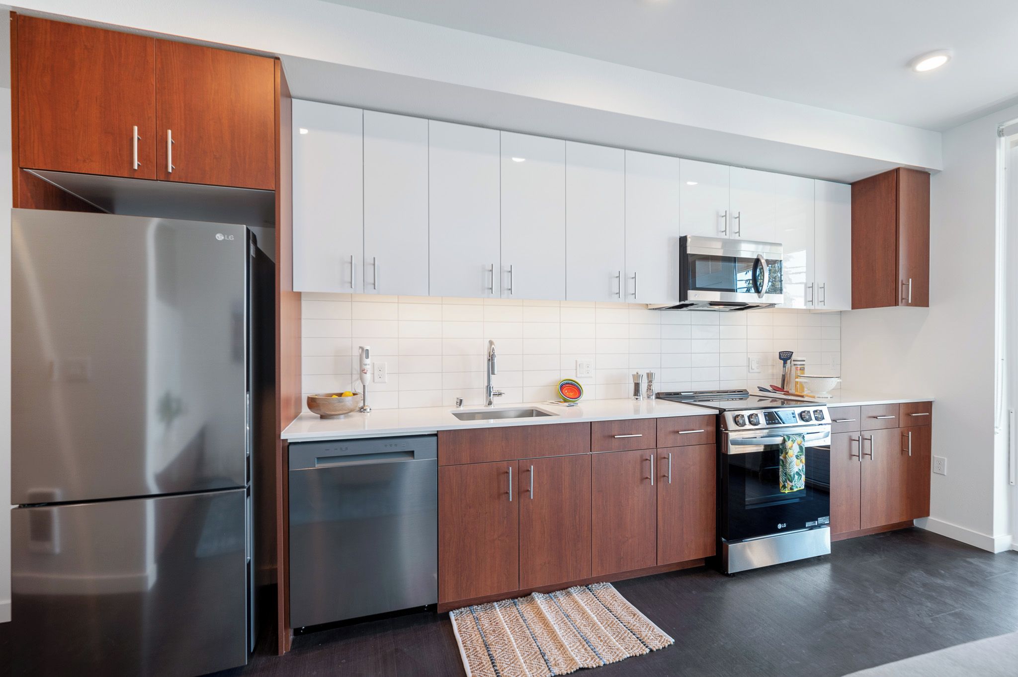 A modern kitchen with stainless steel appliances, white cabinetry, and a tiled backsplash.