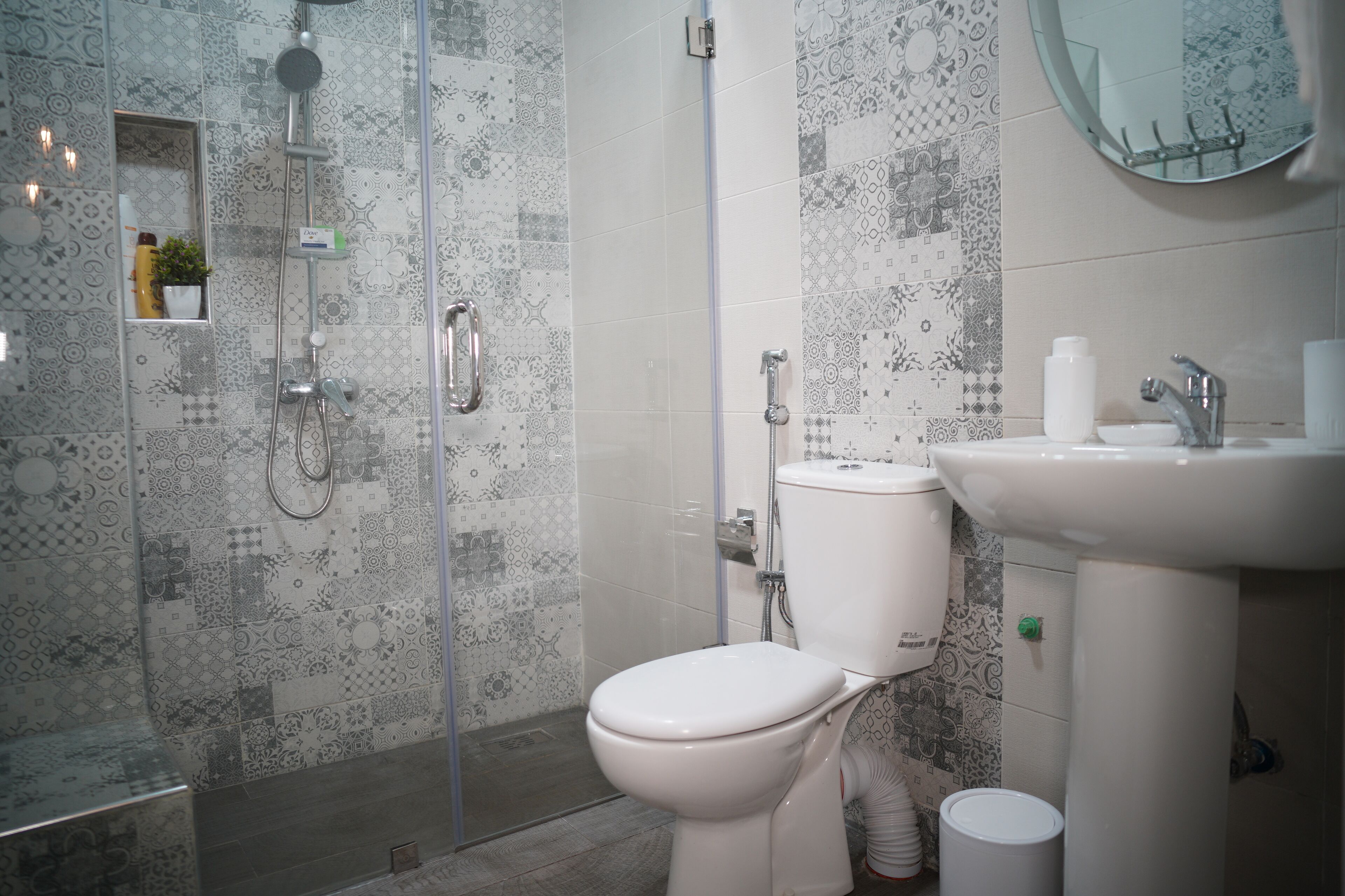 Un baño con ducha, inodoro, lavabo y espejo.