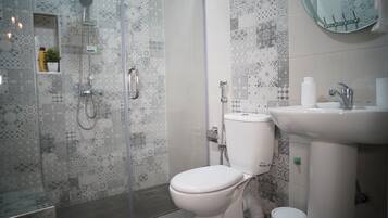 Un baño con ducha, inodoro, lavabo y espejo.