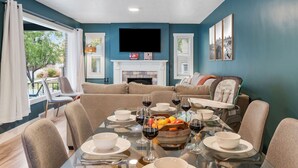 Un comedor con una mesa dispuesta para seis personas, una chimenea y un televisor montado en la pared.