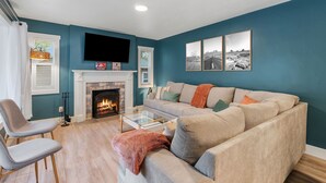 Una sala de estar con paredes color turquesa, una chimenea, un sofá y un televisor de pantalla plana.