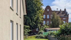 Une cour avec un bâtiment en briques, une pelouse et une clôture.