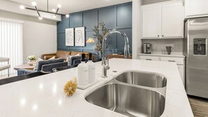 Una cucina moderna con un'isola grande, lavello in acciaio inossidabile e frigorifero integrato.