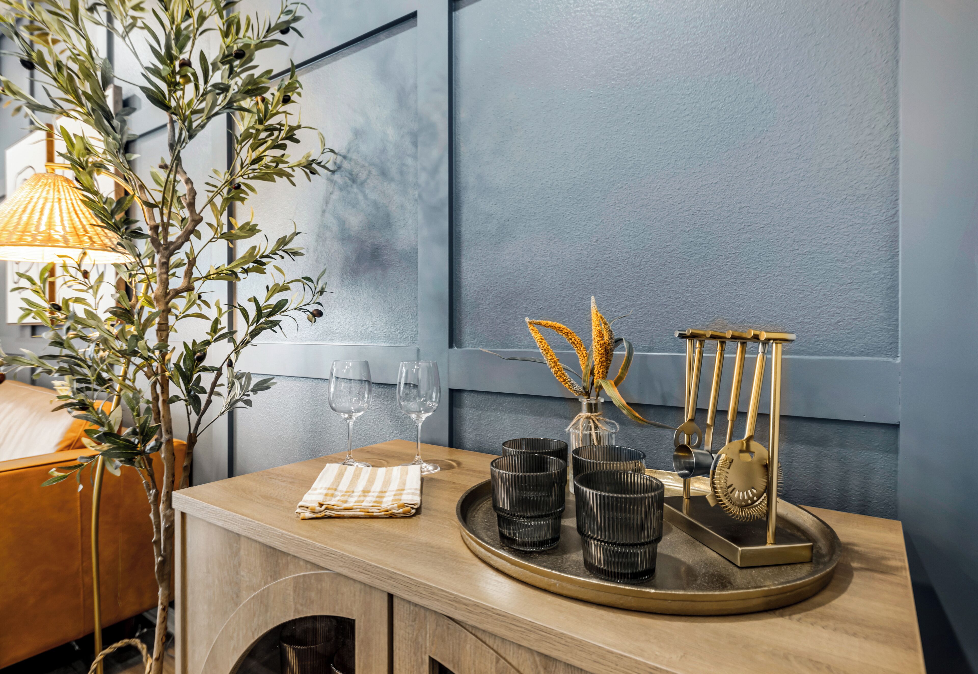 Une table en bois sur laquelle se trouve un plateau contenant des vases noirs, un présentoir décoratif et un vase avec des fleurs séchées.