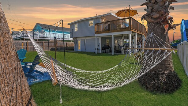 A house with a balcony, a hammock, and a tree.