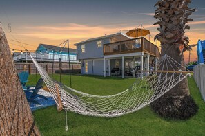 A house with a balcony, a hammock, and a tree.