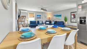 A dining area with a wooden table set for four, surrounded by white chairs.