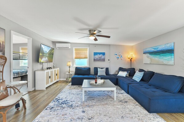 A living room with a blue sofa, white coffee table, and a ceiling fan.