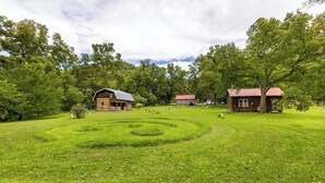 A rustic cabin with a wooden exterior and a red roof, surrounded by a well-maintained grassy area and trees.