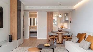 A modern kitchen with a dining area, a sofa, and a TV.