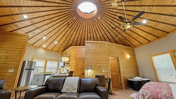 Ein gemütliches Blockhaus-Interieur mit schrägem Dach, Essbereich, Küche, Bad und einer Sitzecke.