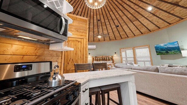A modern kitchen with a stainless steel stove, a microwave, and a wooden ceiling.