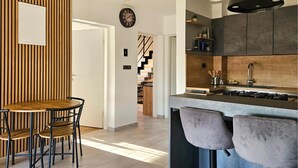A modern kitchen with a central island, bar stools, and a dining area with a wooden table and chairs.