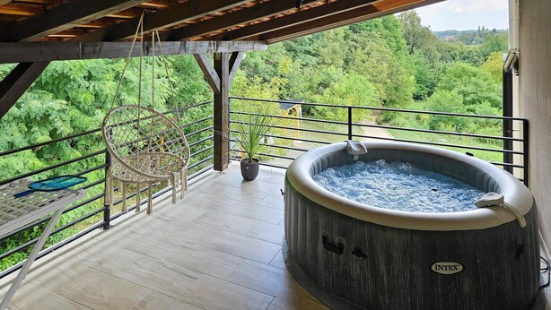 A hot tub on a wooden deck with a view of a forest.