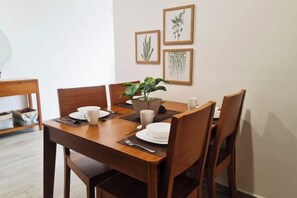 Enjoy meals in this cozy dining area with a table for four, surrounded by framed botanical prints and a potted plant.
