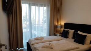 A hotel room with a large bed, a nightstand with a lamp, and a view of the outdoors through the window. - Apartment in Miedzyzdroje With Sea View (Międzyzdroje)
