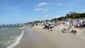 A beach with people, umbrellas, and a pier in the background. - Apartment in Miedzyzdroje With Sea View (Międzyzdroje)