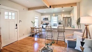 A spacious living area with a wooden floor, a dining table, and a kitchen in the background. - Cheerful 3 bedroom Villa with Backyard Oasis (Spokane)