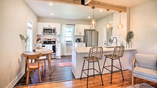 A modern kitchen with white cabinets, a central island, and bar stools. - Cheerful 3 bedroom Villa with Backyard Oasis (Spokane)