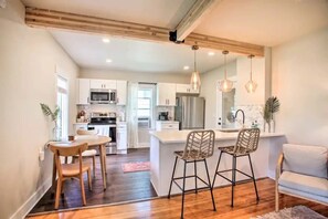 A modern kitchen with white cabinets, a central island, and bar stools. - Cheerful 3 bedroom Villa with Backyard Oasis (Spokane)